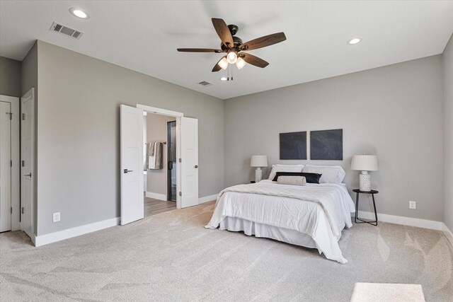 bedroom featuring ceiling fan, ensuite bathroom, and light carpet