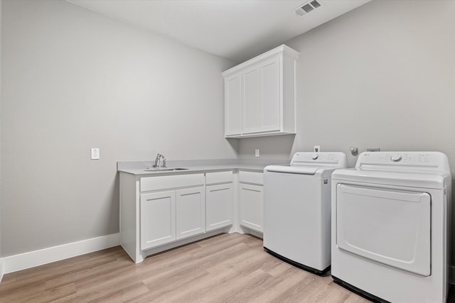 washroom with cabinets, sink, independent washer and dryer, and light hardwood / wood-style flooring