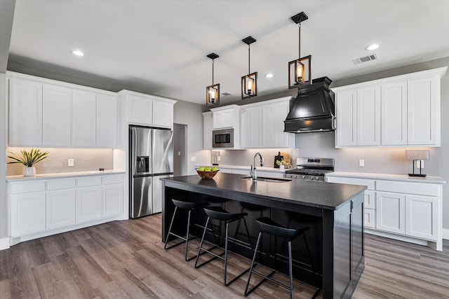 kitchen featuring a kitchen island with sink, hardwood / wood-style floors, custom exhaust hood, stainless steel appliances, and sink