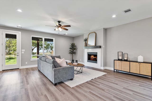 living room with light hardwood / wood-style flooring and ceiling fan