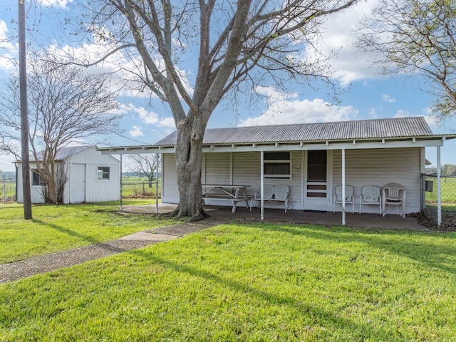 back of house featuring a lawn, an outdoor structure, and covered porch