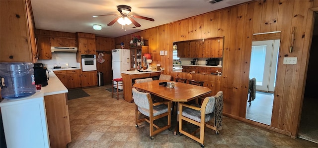 tiled dining space featuring wooden walls and ceiling fan