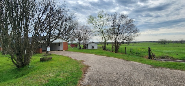 view of front of home with a front lawn, an outdoor structure, and a rural view