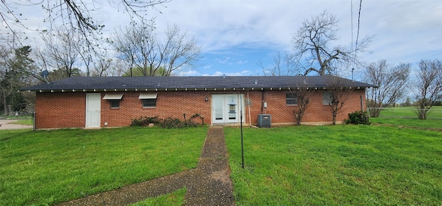 rear view of house with central AC and a yard