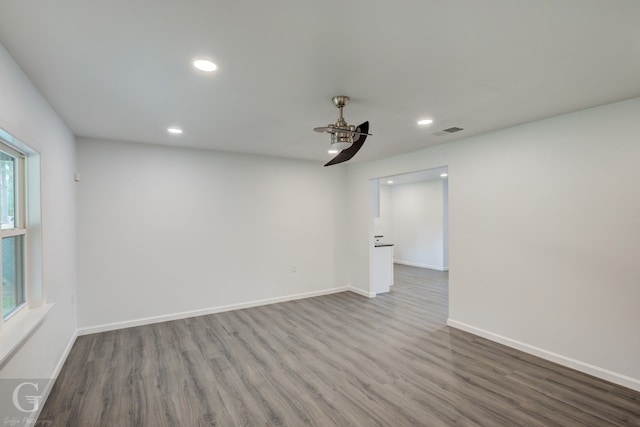 empty room featuring dark hardwood / wood-style flooring, a healthy amount of sunlight, and ceiling fan