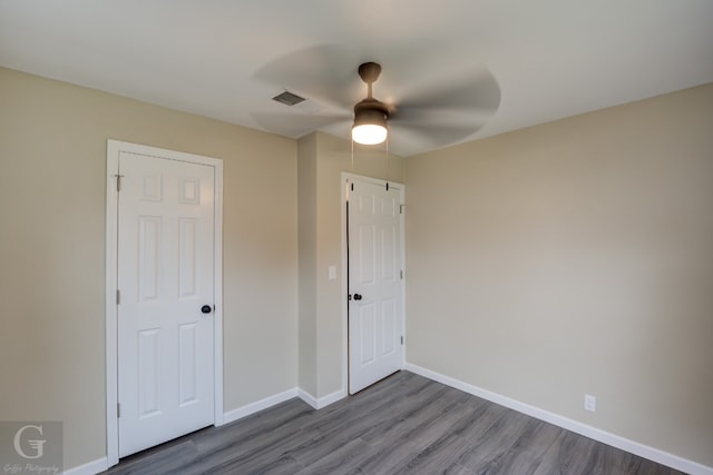 unfurnished bedroom with ceiling fan, dark hardwood / wood-style floors, and a closet