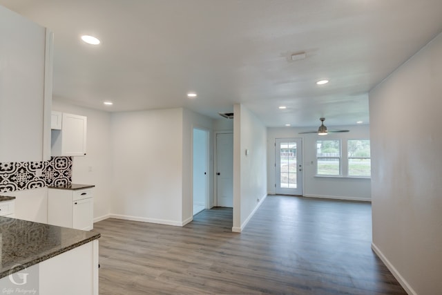 kitchen featuring dark stone counters, tasteful backsplash, wood-type flooring, ceiling fan, and white cabinetry