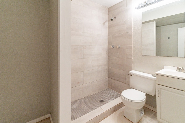 bathroom with a tile shower, vanity, toilet, and tile patterned floors