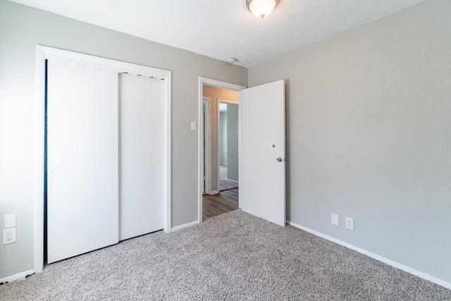 unfurnished bedroom featuring carpet floors, a textured ceiling, and a closet