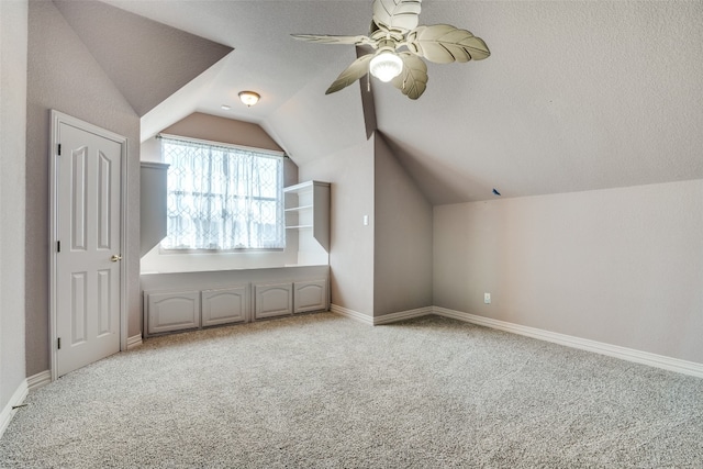 additional living space featuring a textured ceiling, ceiling fan, vaulted ceiling, and light colored carpet