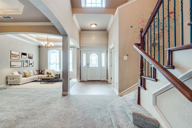 carpeted foyer with plenty of natural light, a tray ceiling, ornamental molding, and a notable chandelier