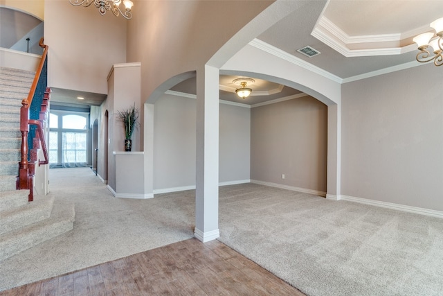 foyer entrance featuring a tray ceiling, ornamental molding, light hardwood / wood-style floors, and a notable chandelier