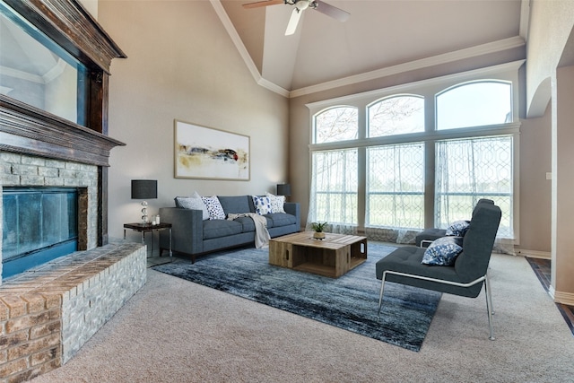 carpeted living room with ornamental molding, ceiling fan, a brick fireplace, and high vaulted ceiling