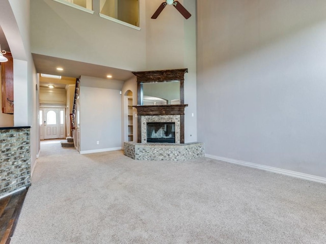 102 Apollo Trl, Aurora, TX 76078 - unfurnished living room featuring ceiling fan, baseboards, carpet flooring, a high ceiling, and a stone fireplace