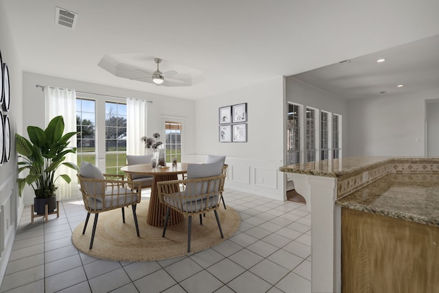 dining space with a raised ceiling, ceiling fan, and light tile patterned floors