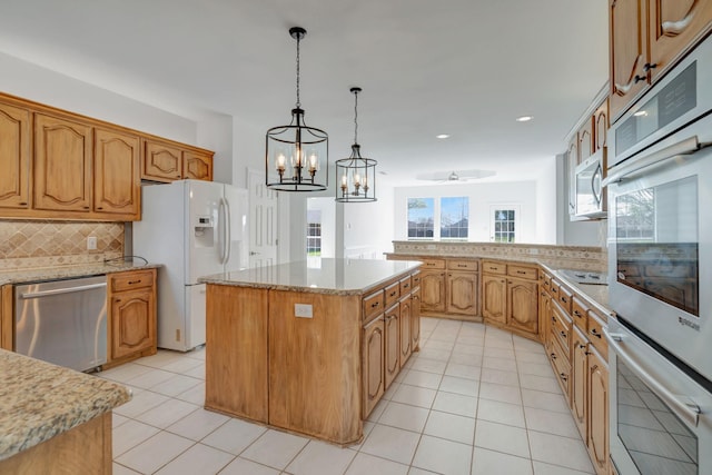 kitchen featuring appliances with stainless steel finishes, backsplash, decorative light fixtures, a chandelier, and a center island