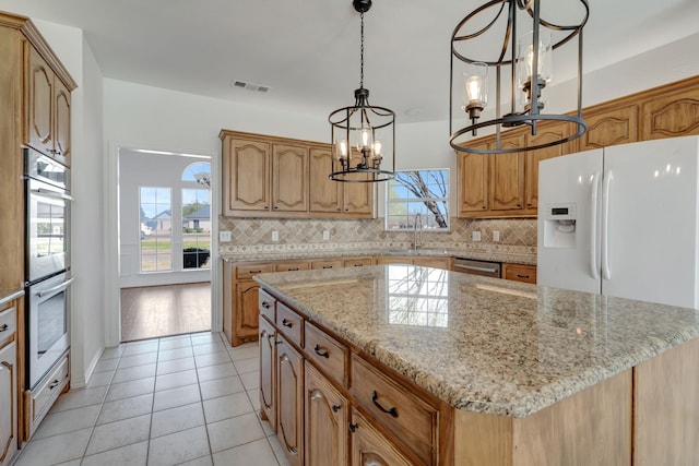 kitchen with a center island, an inviting chandelier, light tile patterned floors, and appliances with stainless steel finishes