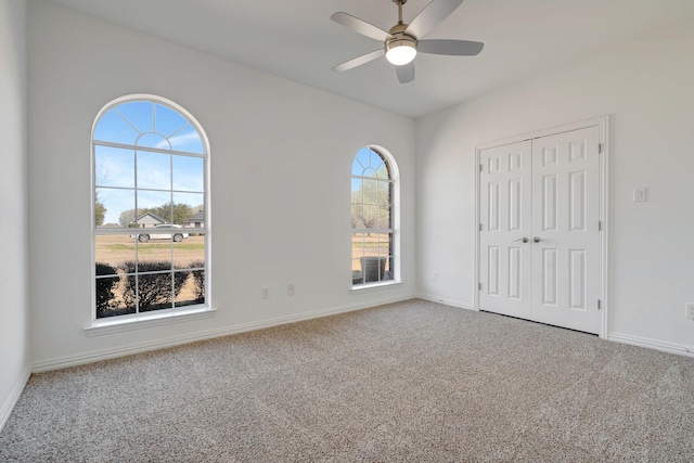 carpeted spare room with a wealth of natural light and ceiling fan