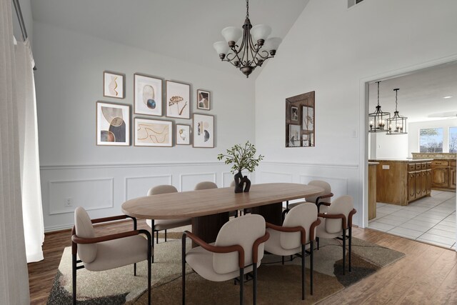 dining room with light hardwood / wood-style floors, lofted ceiling, and a notable chandelier