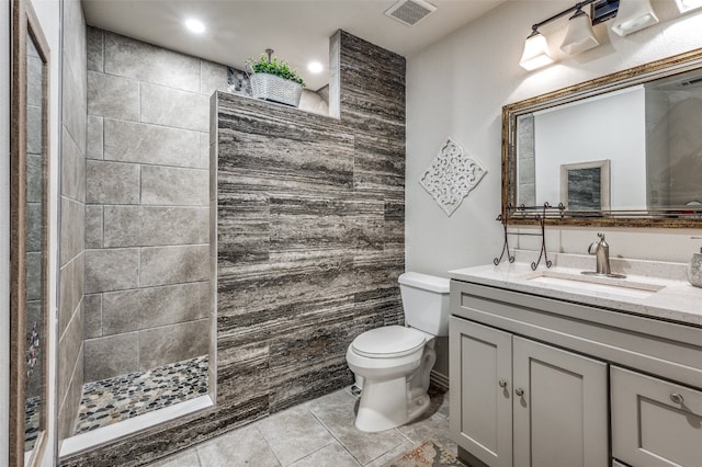 bathroom with tile walls, tile floors, tiled shower, toilet, and vanity