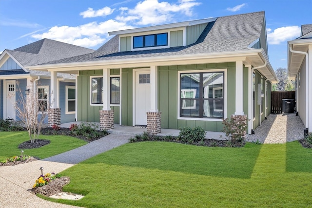 view of front facade featuring a porch, central AC unit, and a front yard