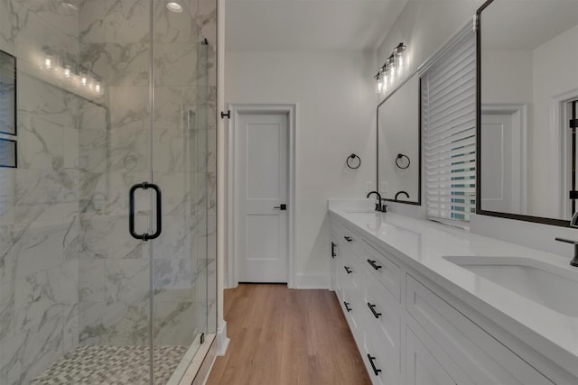 bathroom with walk in shower, oversized vanity, double sink, and wood-type flooring