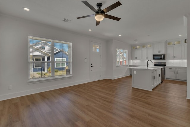 kitchen featuring appliances with stainless steel finishes, ceiling fan, dark hardwood / wood-style flooring, and a center island with sink