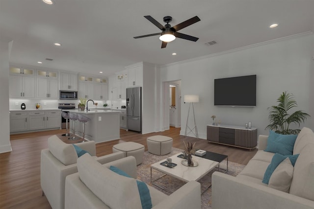 living room with ceiling fan, ornamental molding, and light wood-type flooring