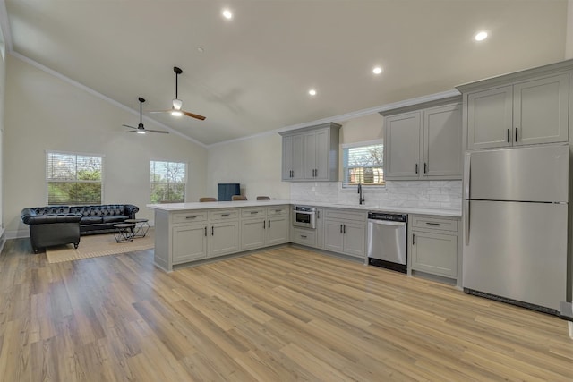 kitchen featuring ornamental molding, ceiling fan, light wood-type flooring, and stainless steel appliances