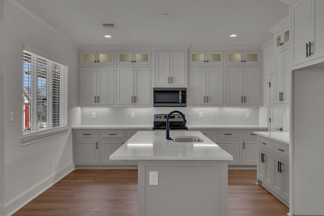 kitchen featuring light hardwood / wood-style flooring, sink, an island with sink, and white cabinets