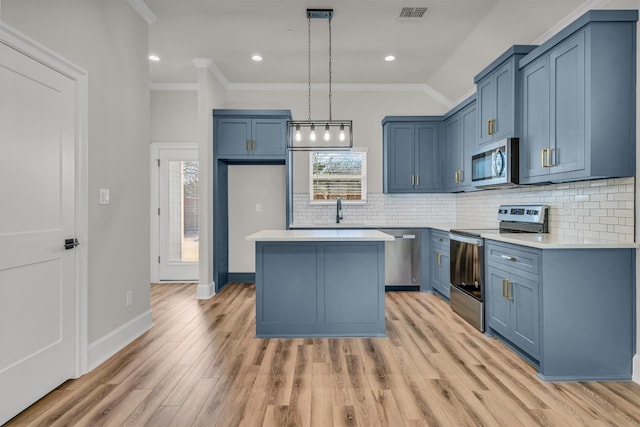 kitchen featuring appliances with stainless steel finishes, light hardwood / wood-style flooring, ornamental molding, and a kitchen island