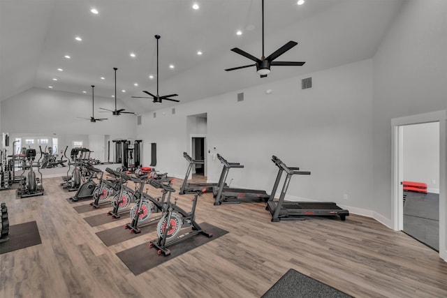 exercise room with light hardwood / wood-style flooring, ceiling fan, and high vaulted ceiling