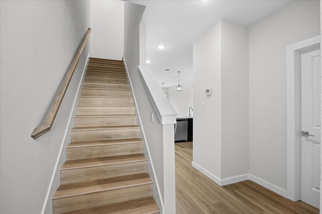 stairs featuring sink and hardwood / wood-style floors