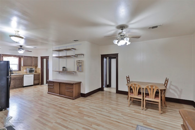 kitchen featuring light hardwood / wood-style floors, black fridge, white dishwasher, and ceiling fan