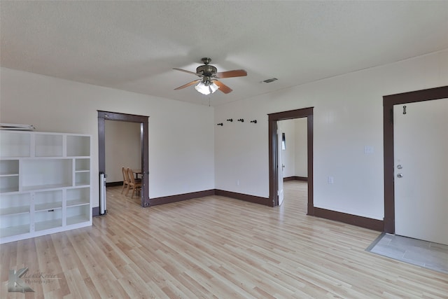 empty room with a textured ceiling, ceiling fan, and light wood-type flooring