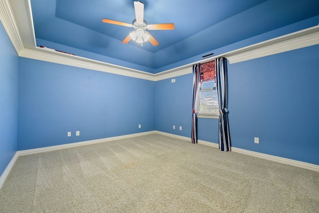 carpeted empty room with a raised ceiling, crown molding, and ceiling fan