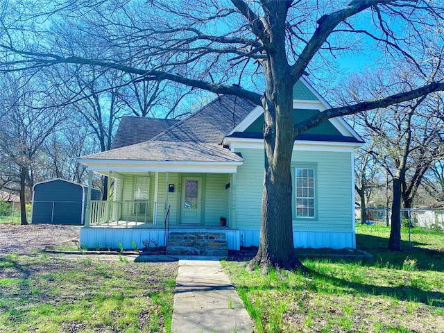 view of front facade with a porch, a front yard, and a shed