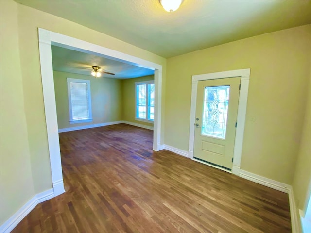 foyer entrance with ceiling fan and dark wood-type flooring