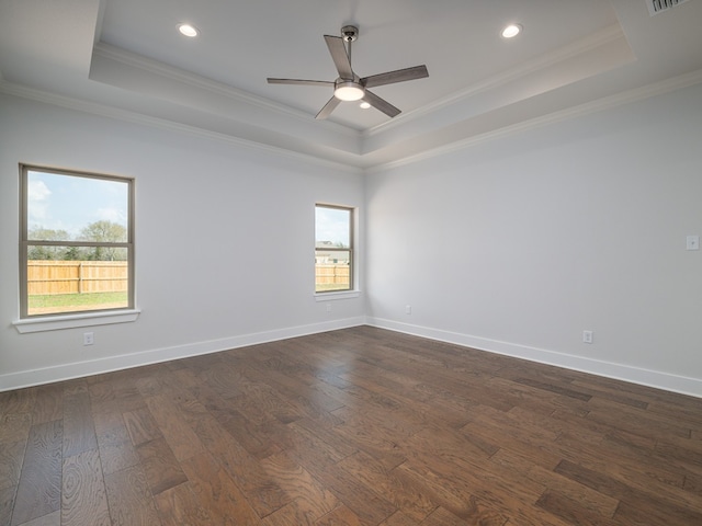 empty room featuring ornamental molding, dark wood-type flooring, ceiling fan, and a tray ceiling