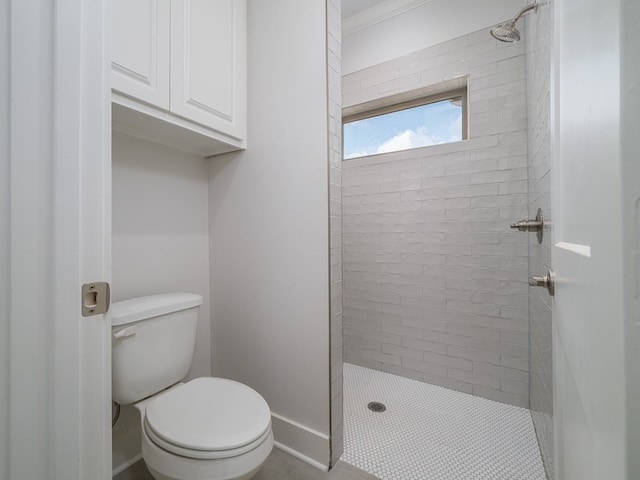 bathroom featuring crown molding, a tile shower, and toilet