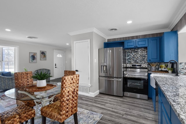 kitchen featuring light hardwood / wood-style floors, tasteful backsplash, crown molding, stainless steel appliances, and blue cabinets