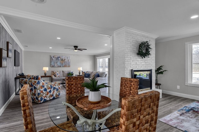 dining area with ornamental molding, a fireplace, ceiling fan, and dark wood-type flooring