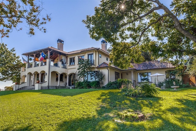 back of property with a yard and a balcony