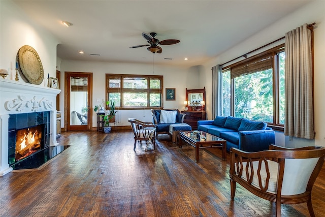 living room with ceiling fan, a fireplace, and dark wood-type flooring