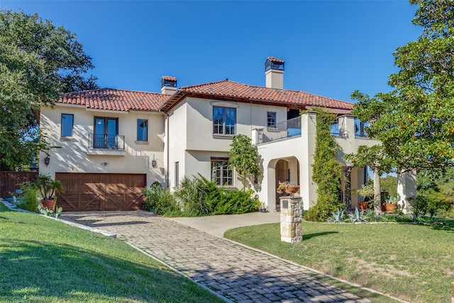 mediterranean / spanish house featuring a garage, a balcony, and a front lawn