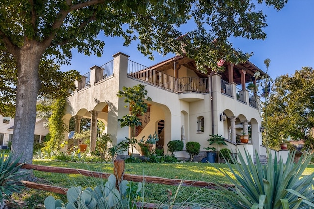 view of front of property with a balcony and a front lawn