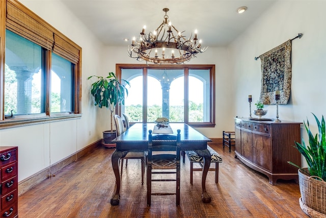 dining area with dark wood-type flooring and a notable chandelier