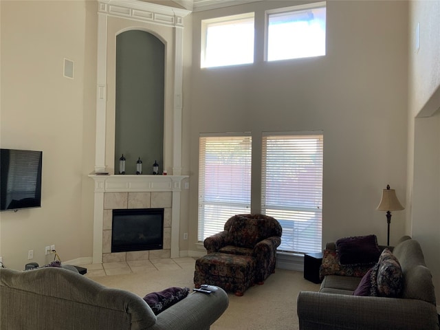 living room featuring light colored carpet, a towering ceiling, and a fireplace