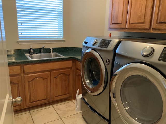 clothes washing area featuring cabinets, sink, light tile floors, and washing machine and dryer