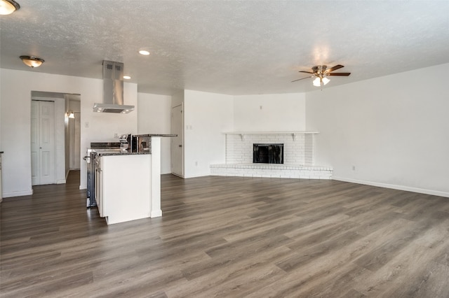 kitchen with ceiling fan, island exhaust hood, dark hardwood / wood-style flooring, a fireplace, and a textured ceiling